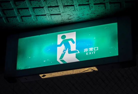 非常口EXITピクトグラム。緑色の非常口サインが暗闇で光っている。